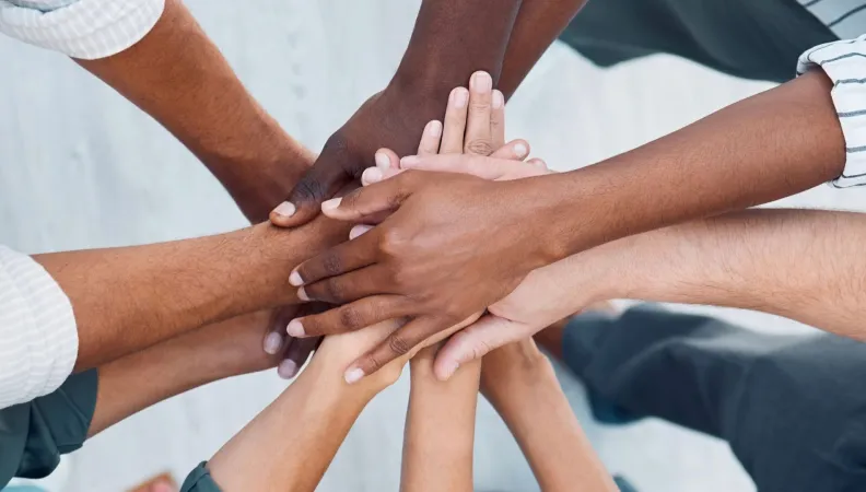 Groupe de personnes, mains les unes sur les autres, prise vue d'en haut. 